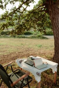 A table with a chair and a book under a tree